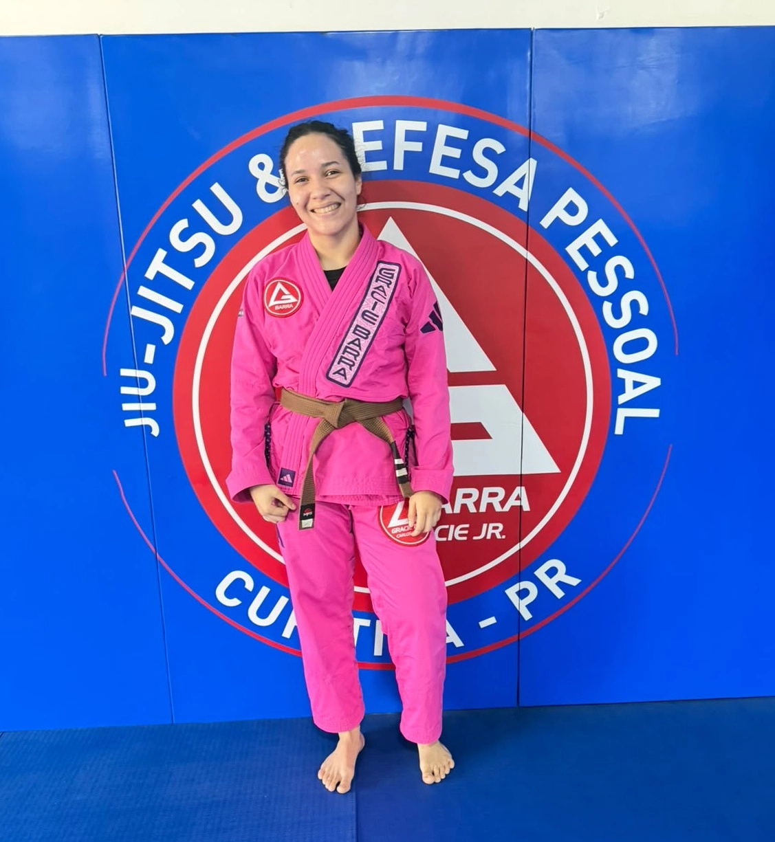 Aryelly Aleixo Soares de kimono e faixa-marrom em ambiente de treino de Jiu-Jitsu